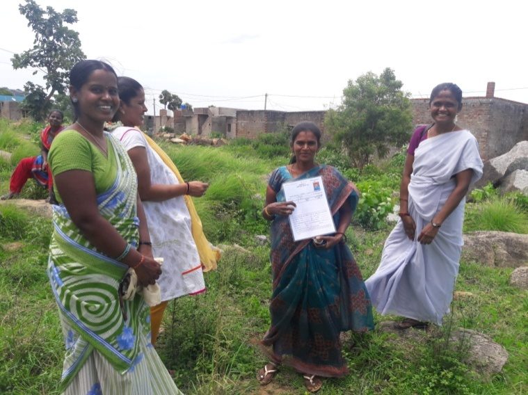 Community members holding their pattas on newly allotted plots